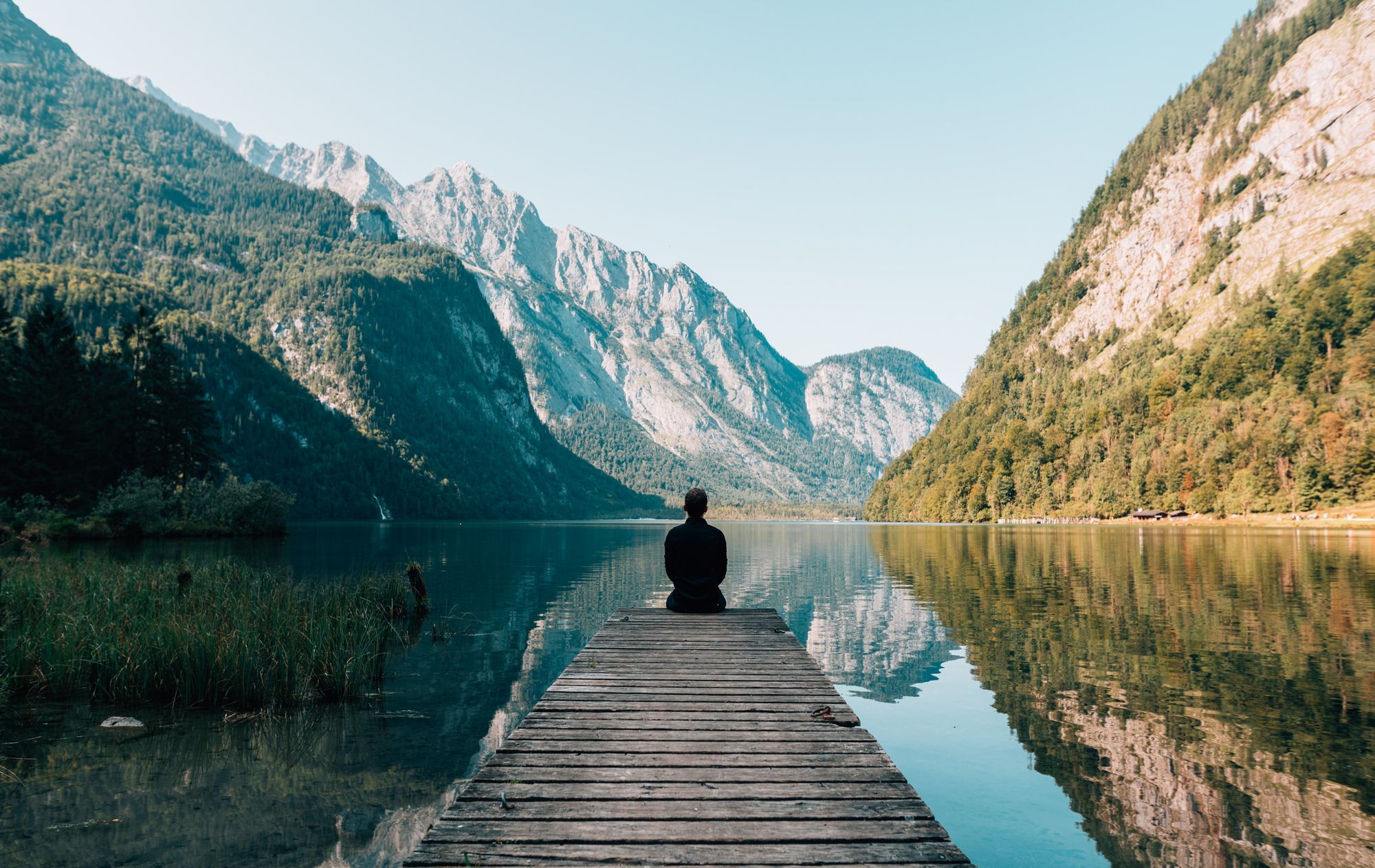 Man on wharf at serene lake eliminating stress