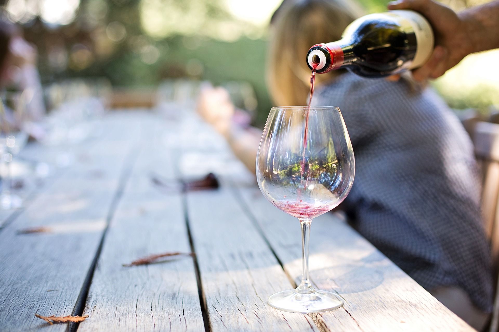 Wine pouring into an empty wine glass on a wooden table