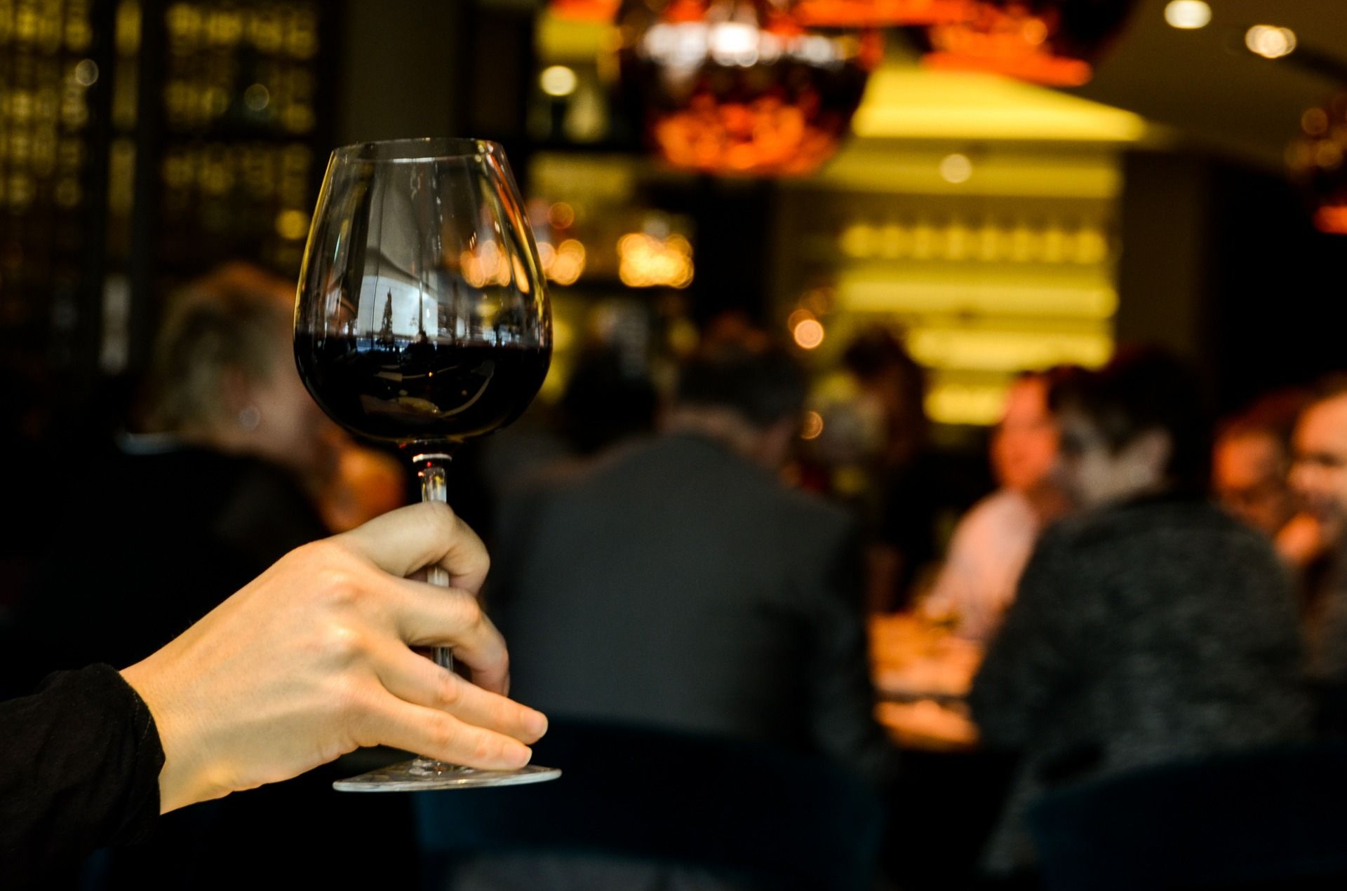 Hand holding a wine glass with red wine; WSET Level 2 exam