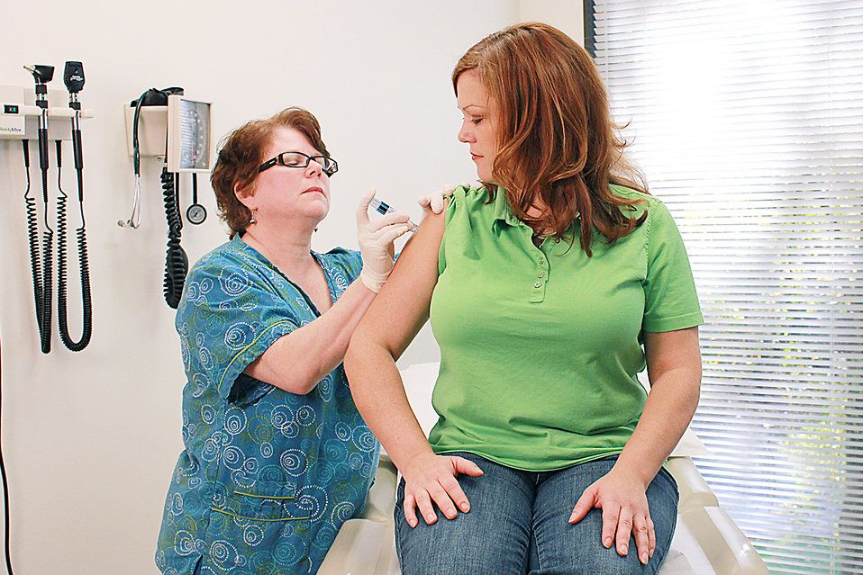 A nurse giving a woman a flu vaccine shot