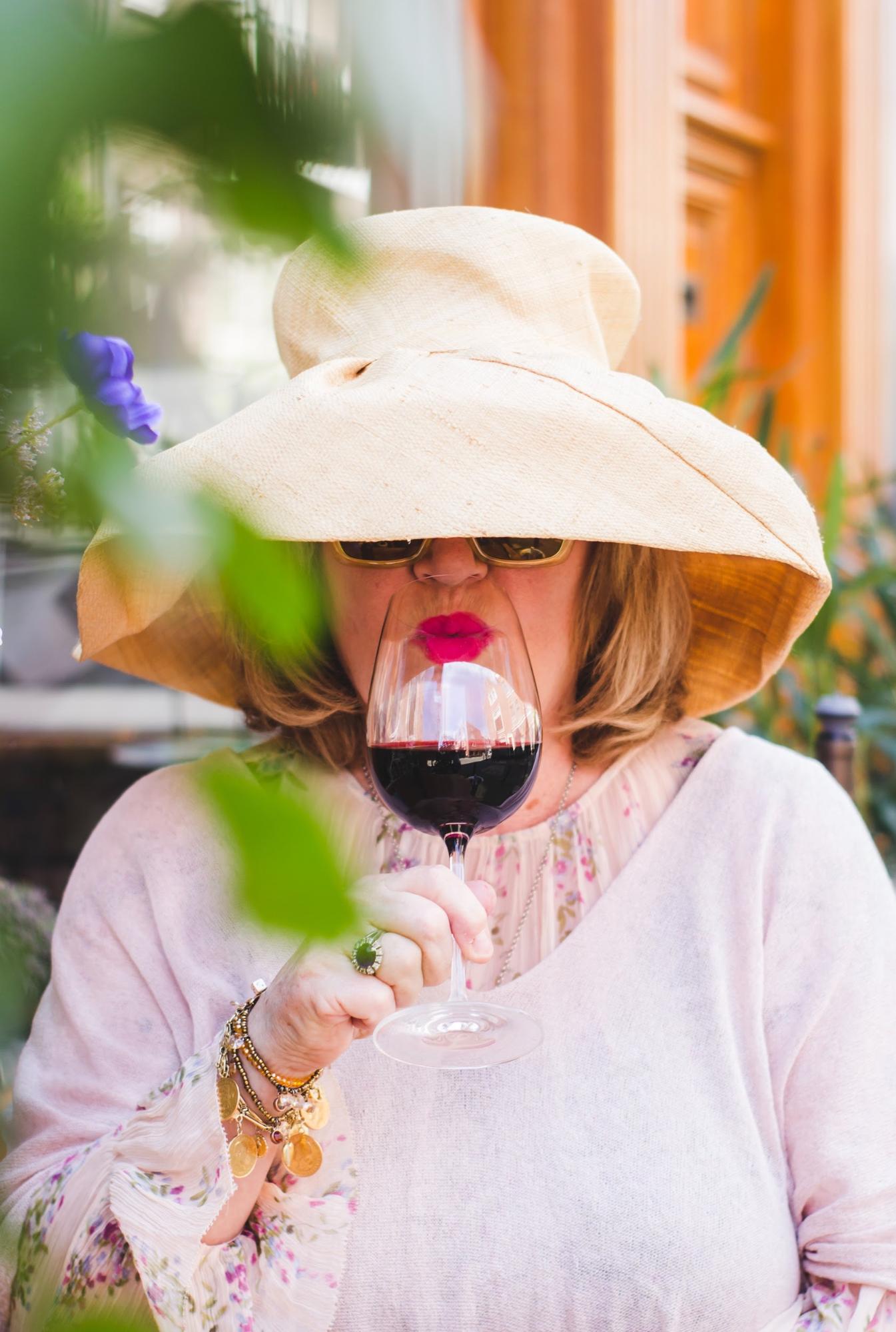 Lady in hat drinking red wine; WSET Level 3 exam