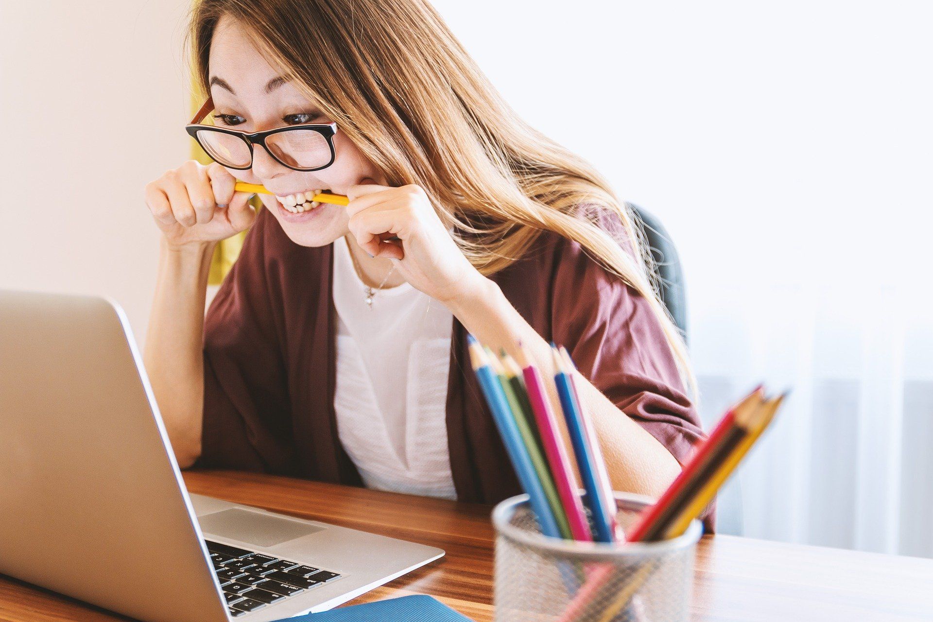 Girl focused on studying chewing on pencil in front of laptop