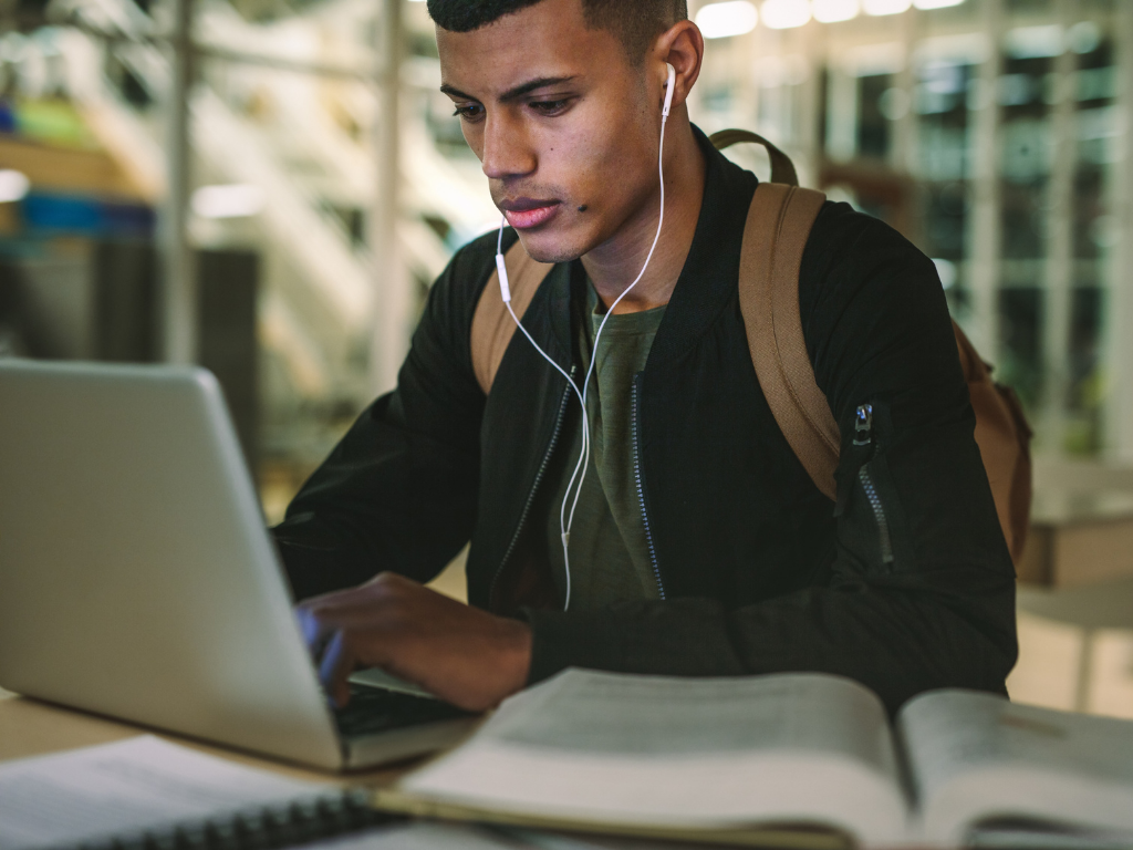 Hombre estudiando frente a una computadora portátil para convertirse en un entrenador personal certificado por NASM 