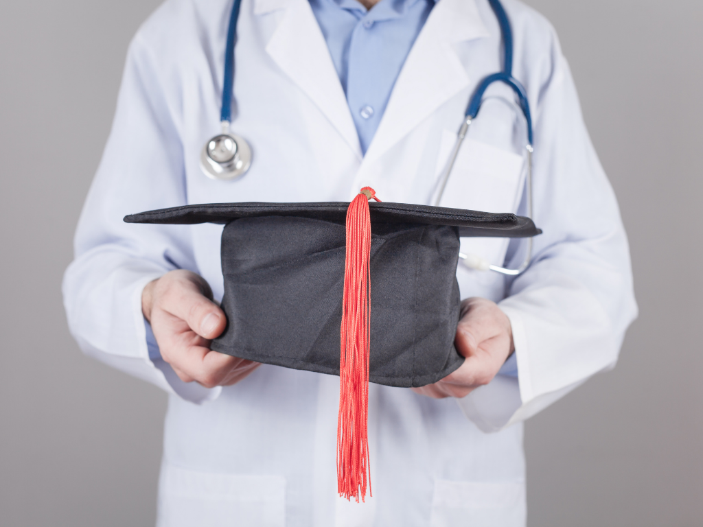 Person holding graduation cap; How to study for the MCAT