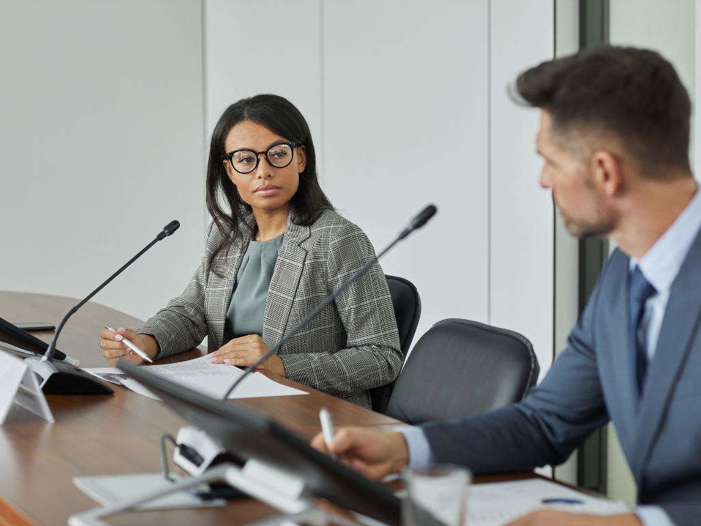 2 lawyers in business attire at a desk getting ready to debate