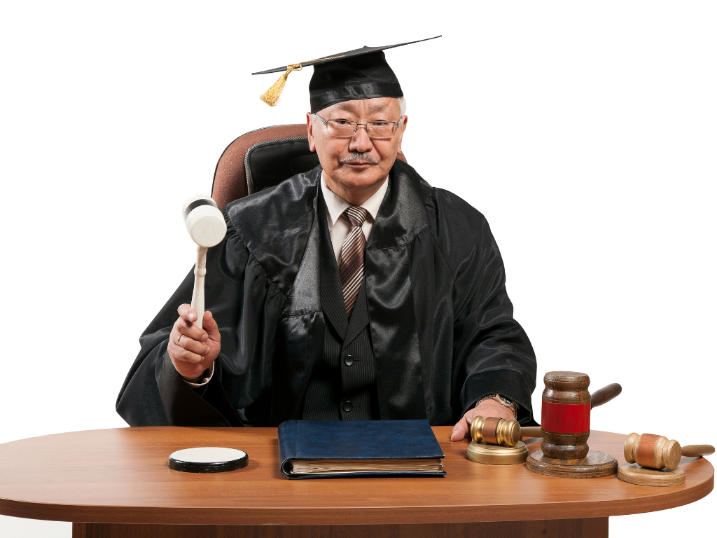 Judge sitting at a desk with gavel in hand raised.