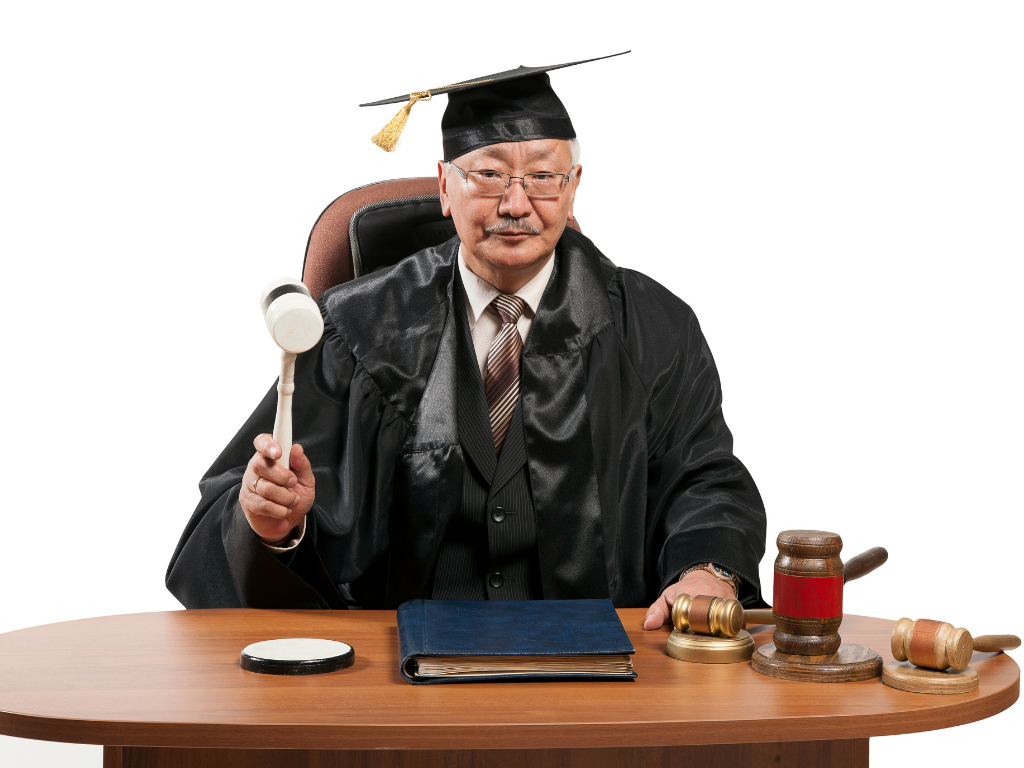 Judge sitting at a desk with gavel in hand raised. 