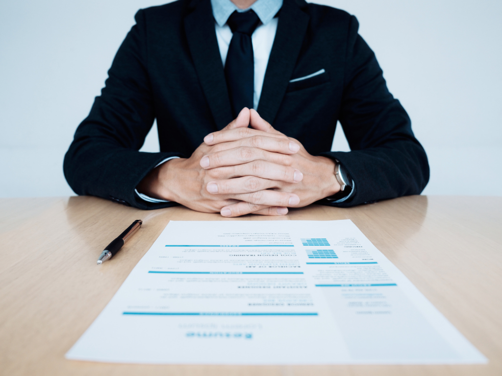 man in suit sitting a table with a resume in front of him for law firm interview