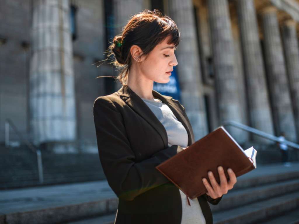 woman reading law book on steps of government building