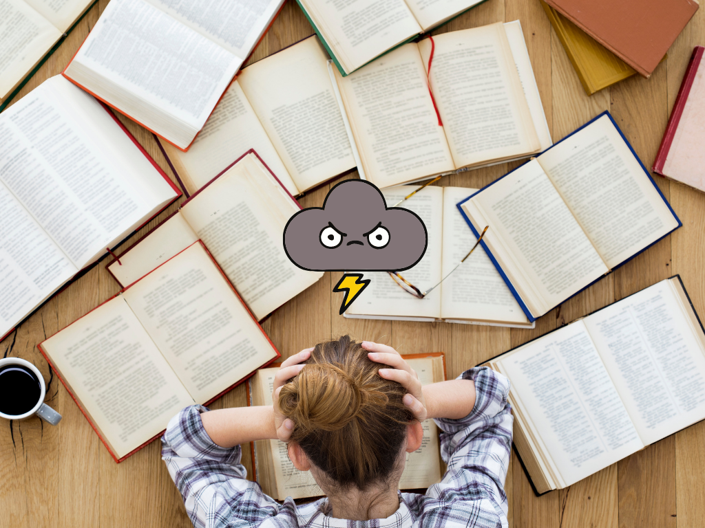 Woman in a plaid shirt holding head in hands in a pile of books with a storm cloud over her head.