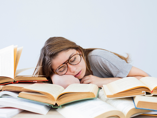 Girl sleeping on an a pile of open books