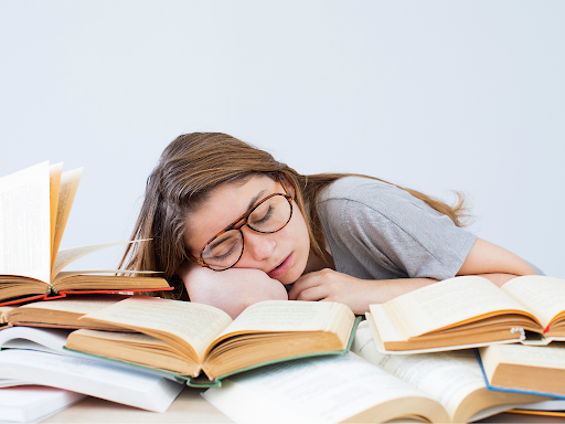 Niña durmiendo sobre una pila de libros abiertos