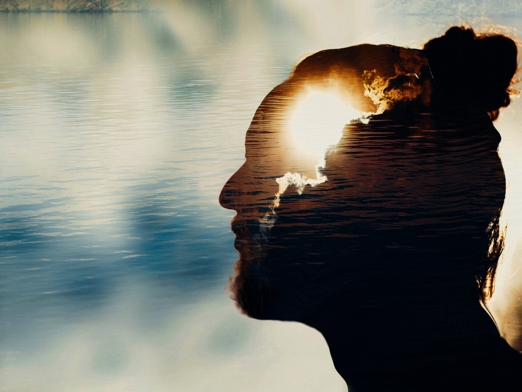 a side profiel of a face with the sun shown in the spot for brain with clouds in the sky