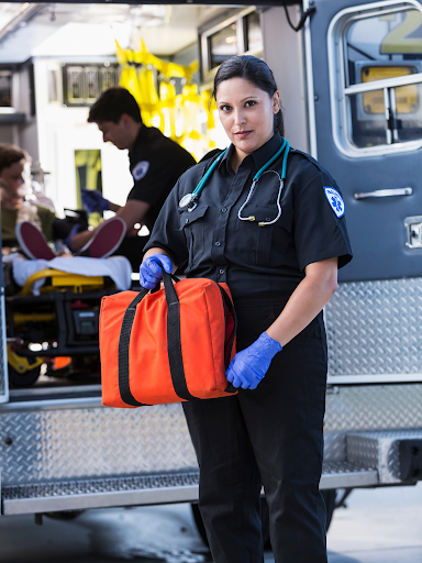 EMS professional holing an orange back outside of an ambulance