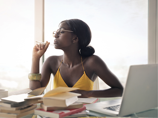 Student studying for EMT surrounded by books and an open laptop