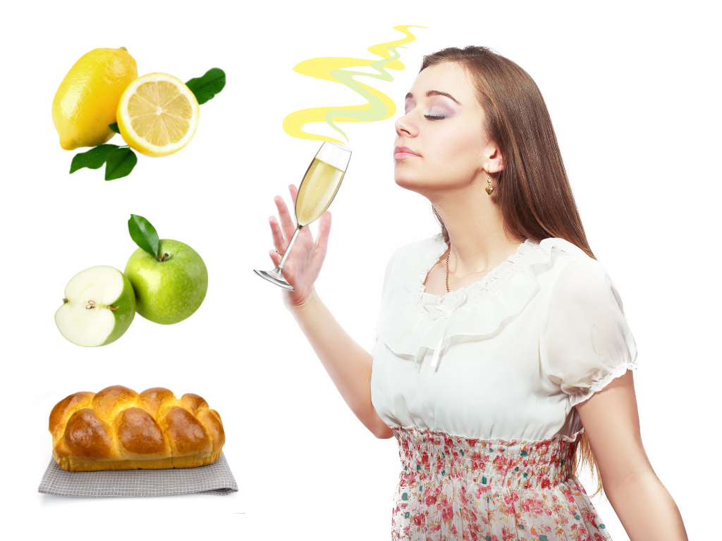 Woman smelling a glass of champagne with lemon, apple, and bread next to her as ideas of aromas