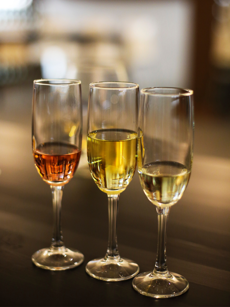 3 different champagnes sitting in glasses on a table next to each other.