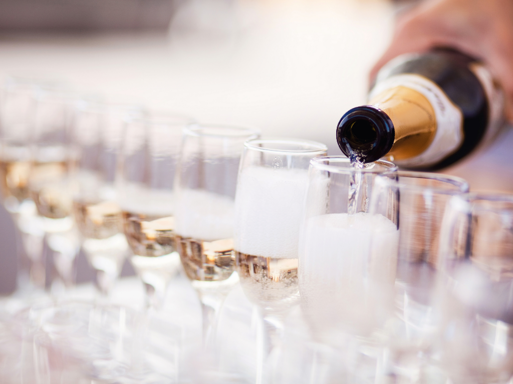 Champagne pouring from a bottle into flute glasses