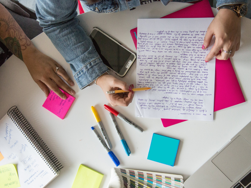 Students writing a paper at a table with markers and post its and paper