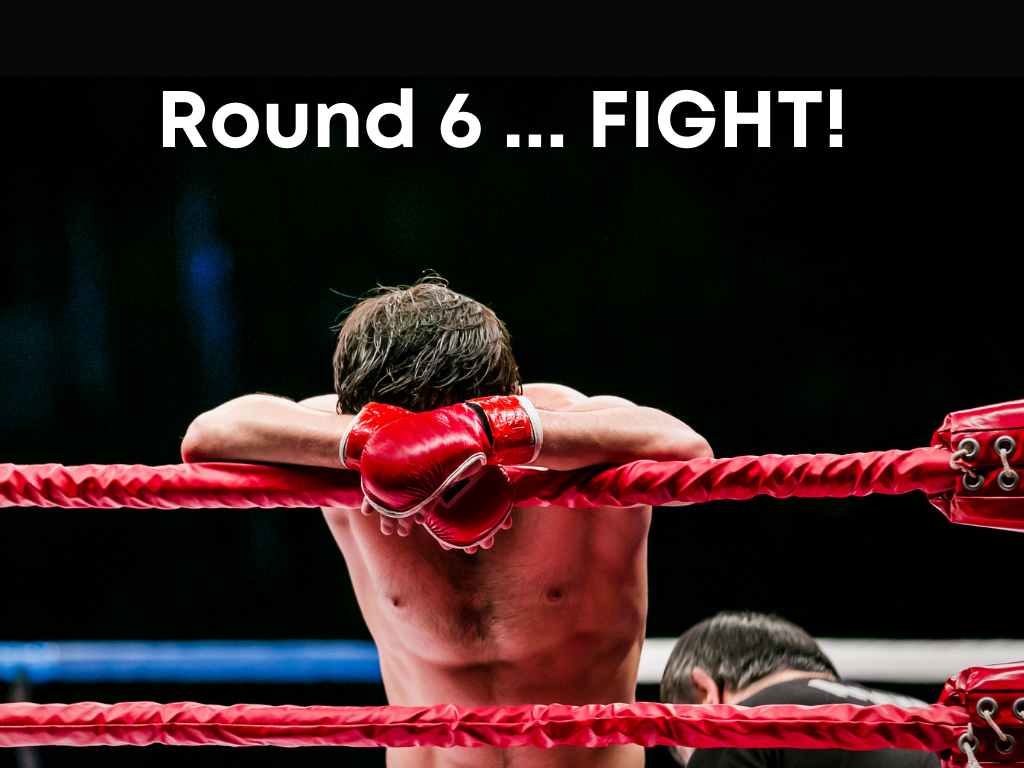 Male boxer leaning on a rope inbetween rounds with red gloves on