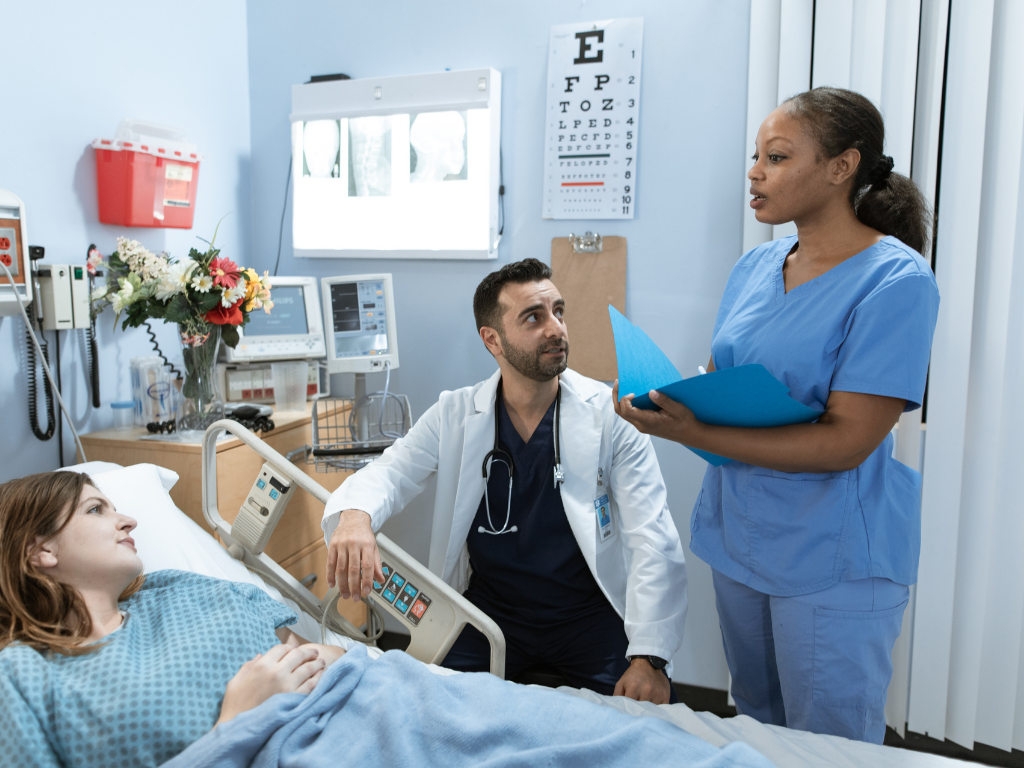 A nurse and doctor standing beside a patient's hospital bed, explaining lab results