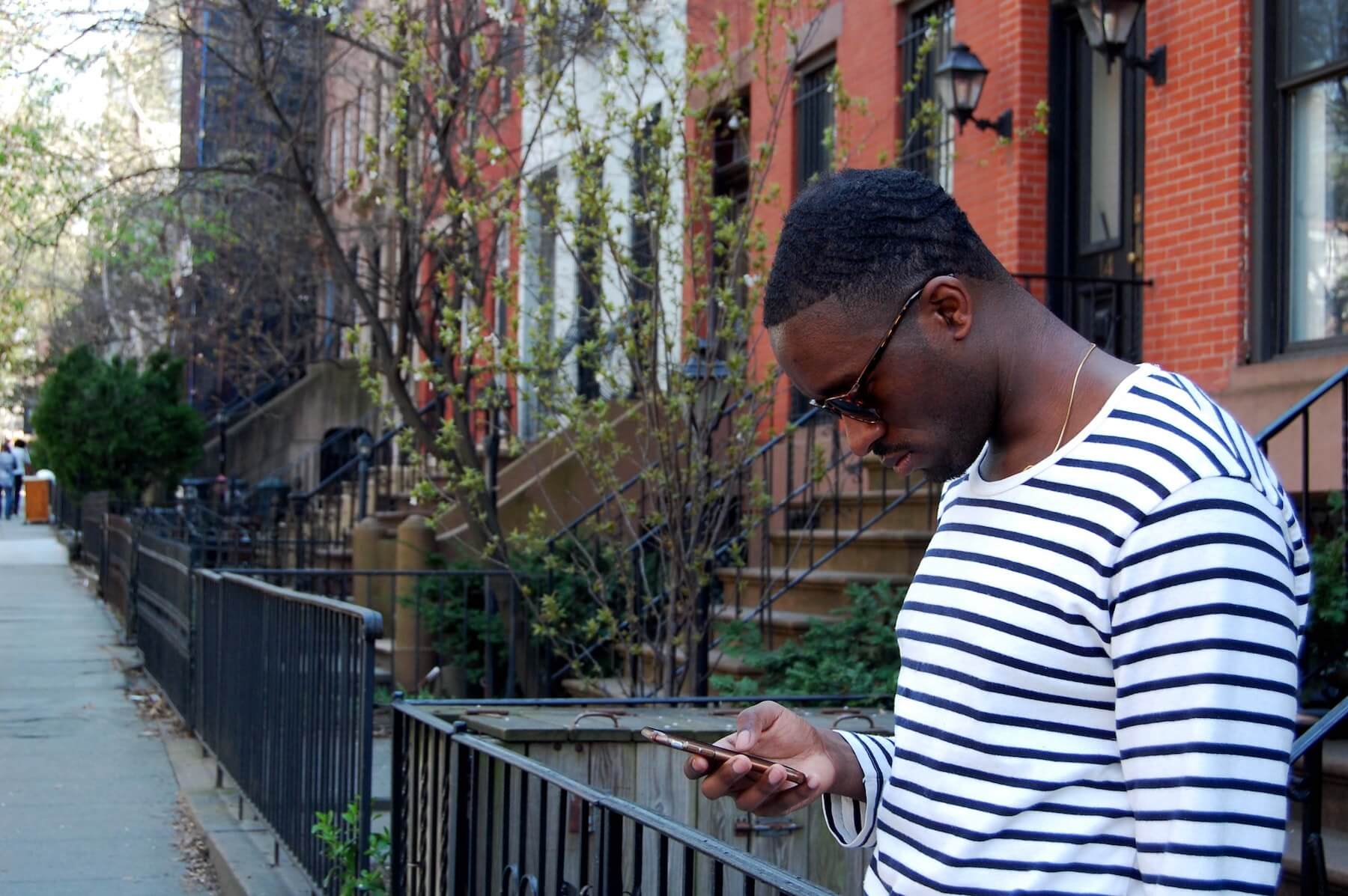 Man standing on a city street, focused on studying flashcards on his smartphone.